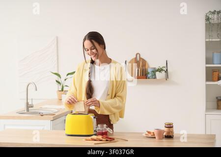 Eine junge Frau, die Toast in der modernen Küche macht Stockfoto
