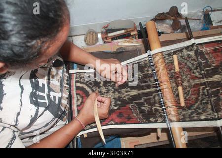 Nahaufnahme eines balinesischen Handwerkers, der traditionelles Geringsing-Doppel-Ikat-Textil auf einem Handwebstuhl im Tenganan Pegringsingan Village, Bali, Indonesien webt. Stockfoto