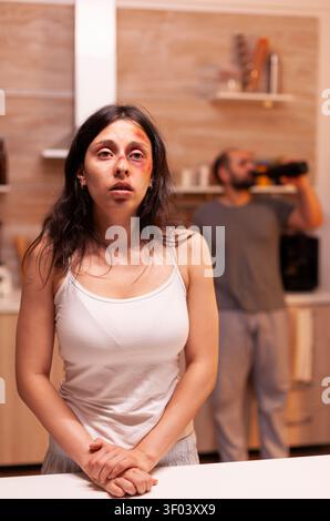 Die hoffnungslose misshandelte Ehefrau steht vor einem betrunkenen aggressiven Ehemann und veranschaulicht Angst, Verletzung und häusliche Gewalttätigkeit in einer verletzlichen Heimatszene. Stockfoto