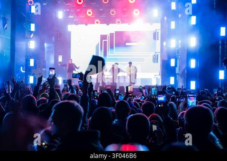 Straße unter freiem Himmel. Ein großes Konzert, eine Menge Leute begrüßen ihre Lieblingsmusiker und machen Fotos auf ihrem Smartphone. Stockfoto