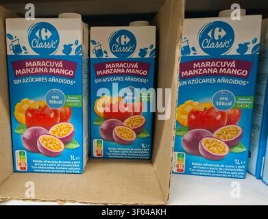 DENIA, SPANIEN - 11. Oktober 2025. Farbenfrohe Saftboxen mit Mango, Passionsfrucht und Apfel sind ordentlich in Regalen in einem Geschäft in Spanien angeordnet. Th Stockfoto