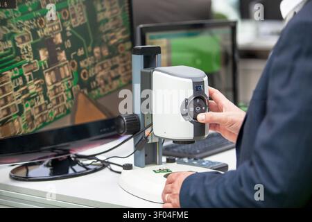 Techniker analysiert PCB-Komponenten mit Digitalmikroskop und Monitor in einem Elektroniklabor, Qualitätskontrolle, Halbleiterinspektion und Vor Stockfoto