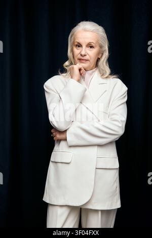 Wunderschön gekleidete reife Frau zeigt Eleganz und Anmut vor dunklem Hintergrund Stockfoto