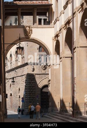 Geflüsterte Geschichten, die sich unter einem sonnenbeschienenen Torbogen aus abgenutztem Stein entfalten (Arezzo, Italien: 11.09.2012) Stockfoto