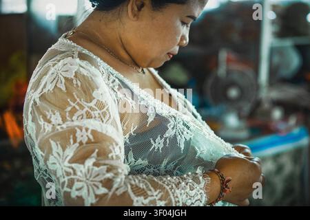 Die Frau passt ihren traditionellen weißen Spitzenkebaya an Stockfoto