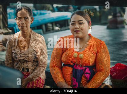 Zwei balinesische Frauen in traditionellem Kebaya sitzen draußen zusammen Stockfoto