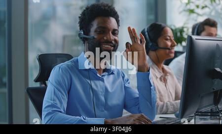 Afroamerikanischer Geschäftsmann mit Headset, der im Callcenter arbeitet, zeigt okay Geste OK Handzeichen Geschäftsmann, der die Kamera ansieht, lächelt in Stockfoto