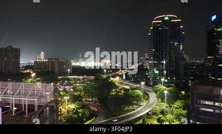 Luftaufnahme der beleuchteten Semanggi-Kreuzung mit Ampelwegen und umliegenden Wolkenkratzern bei Nacht in Kecamatan Setiabudi, Daerah Khus Stockfoto