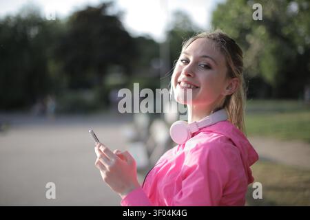 Glückliche junge Frau mit Kopfhörern, die draußen telefonieren Stockfoto