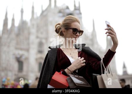 Schicke Frau, die ein Selfie in Mailand mit Einkaufstaschen macht Stockfoto