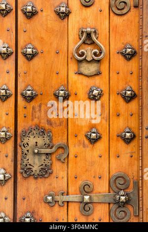 Veraltete Holztür mit verzierten Metallbeschlägen und Nieten Stockfoto