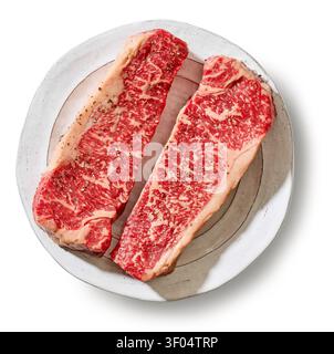Zwei frische, rohe Premium-Wagyu-Rindersteak-Scheiben auf einem Teller isoliert auf weißem Hintergrund, Draufsicht. Hochwertige Fleischstücke aus Marmor auf einem Gericht, Stockfoto