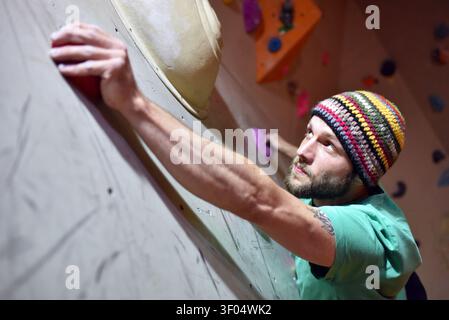 Junge sportliche Mann Bouldern in einer Kletterhalle - indoor Sport Stockfoto