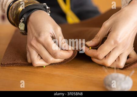 Nahaufnahme der weiblichen Hände, die dickes braunes Tuch feststecken Stockfoto