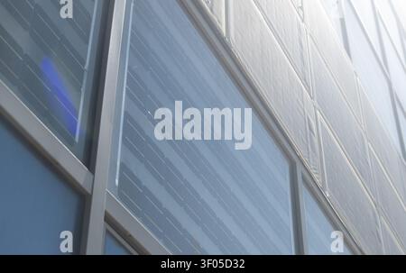 Moderne Gebäudefassade mit integrierten Solarpaneelen, die innovatives Photovoltaik-Design und nachhaltige Architektur bieten. Stockfoto