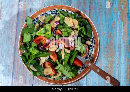 Gesunde vegane Mahlzeit in einer Schüssel, mit frischem Spinat, Tomaten, Pilzen, roter Zwiebel, auf einem rustikalen Holztisch Stockfoto