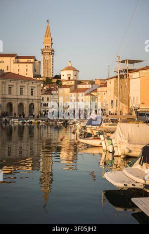 Historischer Glockenturm und farbenfrohe Gebäude, die sich im Hafen von Piran spiegeln Stockfoto