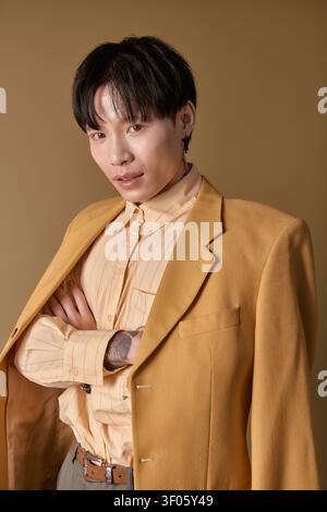 Ein hübscher junger asiatischer Mann in einem stylischen gelben Blazer zeigt sein modisches Selbstbewusstsein. Stockfoto