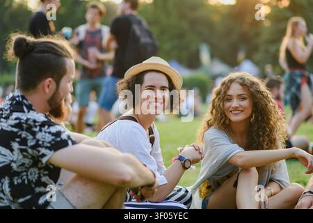 Gruppe junger Freunde, die auf dem Boden beim Sommerfest sitzen. Stockfoto