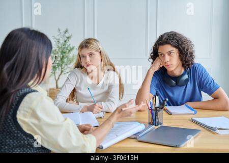 Lehrerin spricht mit gelangweilten Teenagern Stockfoto
