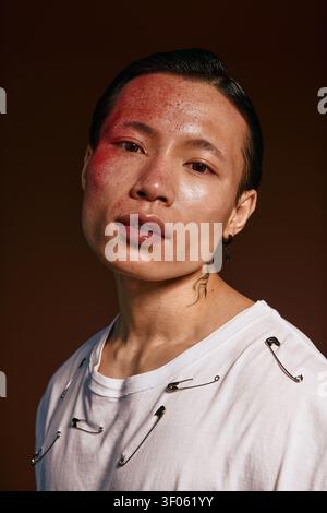 Ein stilvoller junger asiatischer Mann zeigt selbstbewusst sein modisches Outfit vor einer reichen Kulisse. Stockfoto
