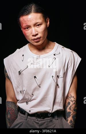 Ein stilvoller junger Mann strahlt Selbstvertrauen aus und trägt ein kreatives, detailreiches Outfit, das auffällt. Stockfoto