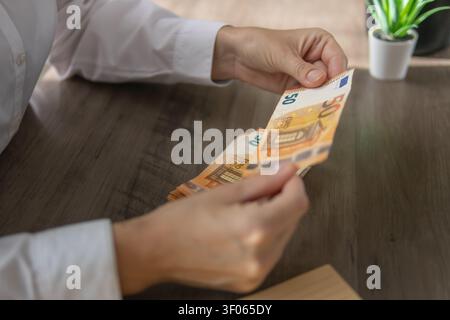 Die Hände einer Person, die einen Stapel von 50 Euro-Banknoten zählt, die Finanzmanagement, europäische Währung, Vermögensaufbau und persönliche Ersparnisse darstellen Stockfoto