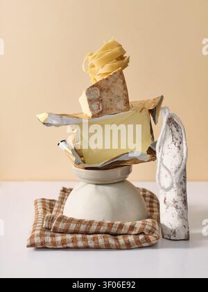 Eine künstlerische Stillleben-Komposition aus Zutaten wie Pasta, Butter, Käse und Salami, kreativ auf einem gefalteten Tuch mit angeordnet Stockfoto