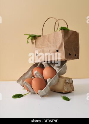 Eine kreative Stillleben-Komposition mit Lebensmitteln, darunter braune Eier und frische Spinatblätter in einer Papiertüte. Ein einzigartiger Ansatz für Essen und Set Stockfoto