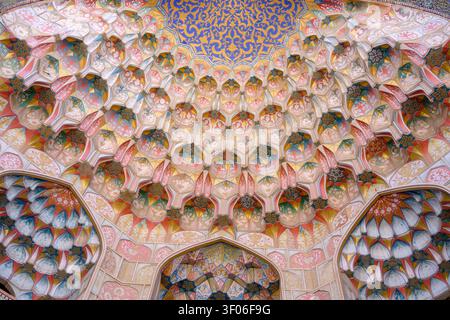 Nahaufnahme einer kunstvollen islamischen Muqarnas-Kuppeldecke mit komplizierten geometrischen Mustern, farbenfrohen Fliesen und symmetrischen architektonischen Elementen Stockfoto