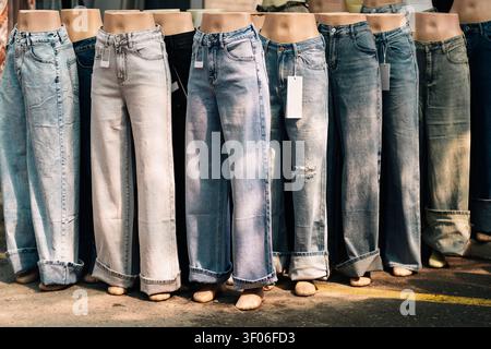 Eine Reihe von Jeans auf den Beinen einer Schaufensterpuppe in einem Bekleidungsgeschäft, die verschiedene Waschungen und Passformen mit hängenden Preisschildern, Outdoor-Market-Style und Fashion-Reta zeigt Stockfoto