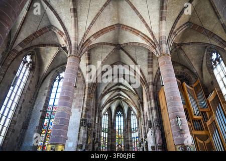 Breite Innenansicht einer gotischen Kathedrale mit gewölbten Rippendecken, Steinsäulen, Buntglasfenstern und einer Orgel. Stockfoto