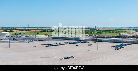 Hutto, TX - 7. April 2026: Luftaufnahme eines großen Industrieparkplatzes und Verladebereichs für Tesla-Elektroautos auf benachbarte Eisenbahngüterwagen Stockfoto