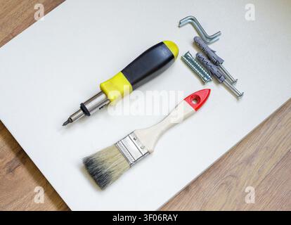 Werkzeugset und Beschläge für die DIY-Möbelmontage zu Hause. DIY-Sanierungsset für die Montage von Schränken auf Laminatböden. Stockfoto