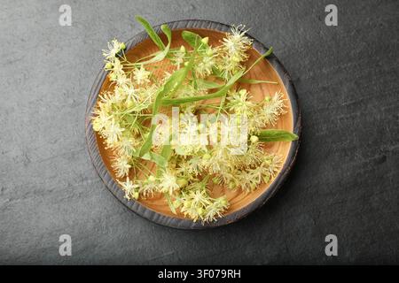 Lindenblüten in einer Schale auf schwarzem Tisch, Blick von oben Stockfoto