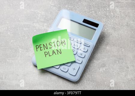 Klebezettel mit den Worten Rentenplan und Taschenrechner auf grauem Tisch, Ansicht von oben Stockfoto