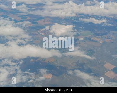 Hochwinkelansicht von landwirtschaftlich genutztem Land mit kreisförmigem Zentrum, Bewässerungsfeldern und verstreuten weißen Wolken über der Landschaft. Stockfoto