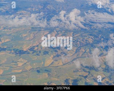 Blick in die Höhe von Fleckenfeldern und sanften Hügeln im Bundesstaat Washington, teilweise bedeckt von verstreuten weißen Wolken. Stockfoto