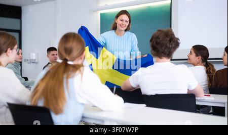 Der Lehrer erzählt den Schülern von Japan und hält eine japanische Flagge in der Hand. Stockfoto