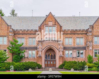 Vorderansicht eines großen akademischen Backsteingebäudes mit einem zentralen gotischen Bogengang, Steindetails und gepflegten grünen Rasenflächen im Bundesstaat Washington. Stockfoto