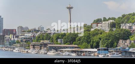 Washington State, JUN 21, 2026 - Blick auf die Seattle Space Needle, die über einer Stadtsilhouette und einem Yachthafen mit gedockten Booten und üppigem Grün aufragt Stockfoto