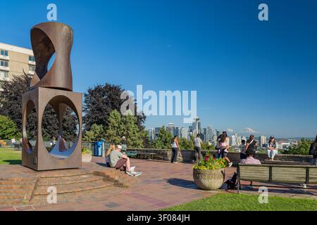Washington Staat, Vereinigte Staaten, 21. JUN 2026 – Menschen entspannen sich auf Bänken und Stufen in der Nähe einer großen abstrakten Metallskulptur mit Blick auf Seattle Stockfoto