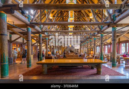 Washington State, 21. JUN 2026 – Besucher schlendern durch die geräumige Lobby einer rustikalen Blockhütte mit großen hölzernen Stützsäulen und Stockfoto