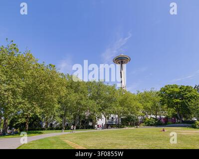 Washington State, 21. Juni 2026 - die Space Needle erhebt sich über grünen Parkbäumen und Rasen in Seattle, Washington, unter einem klaren blauen Himmel. Stockfoto