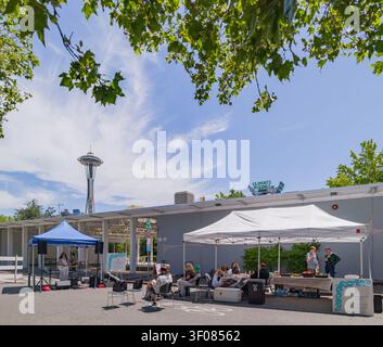 Washington State, USA, 21. Juni 2026 - Menschen, die sich unter weißen Zelten bei einer Veranstaltung im Freien versammeln, wobei die Space Needle im Hintergrund sichtbar ist Stockfoto