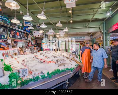 Washington State, USA, 21. Juni 2026 – Kunden stöbern in einem belebten Fischmarkt in Seattle durch eine große Auswahl an frischem Fisch auf Eis. Stockfoto