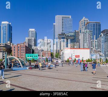 Washington State, USA, 21. Juni 2026 - Fußgänger spazieren über einen gepflasterten plaza in Seattle, Washington, mit einem Spielplatz und einem modernen Wolkenkratzer Stockfoto