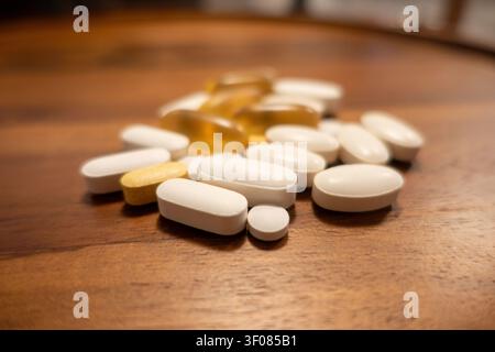 ein Haufen Pillen in verschiedenen Formen und Größen auf einem Holztisch - Tabletten und Gelkapseln, Nahrungsergänzungsmittel und verschreibungspflichtige Medikamente Stockfoto