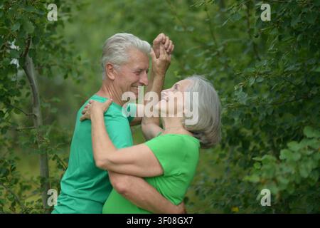 Senior tanzt freudig in üppiger Vegetation, Nahaufnahme seitlich von glücklichen und Momenten in der Natur, Familienbeziehungen und Momente in lebhaftem Licht eingefangen Stockfoto