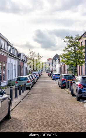 Wohnstraße gesäumt von geparkten Autos und niederländischen Häusern in Schiedam, Südholland, Niederlande. Stockfoto